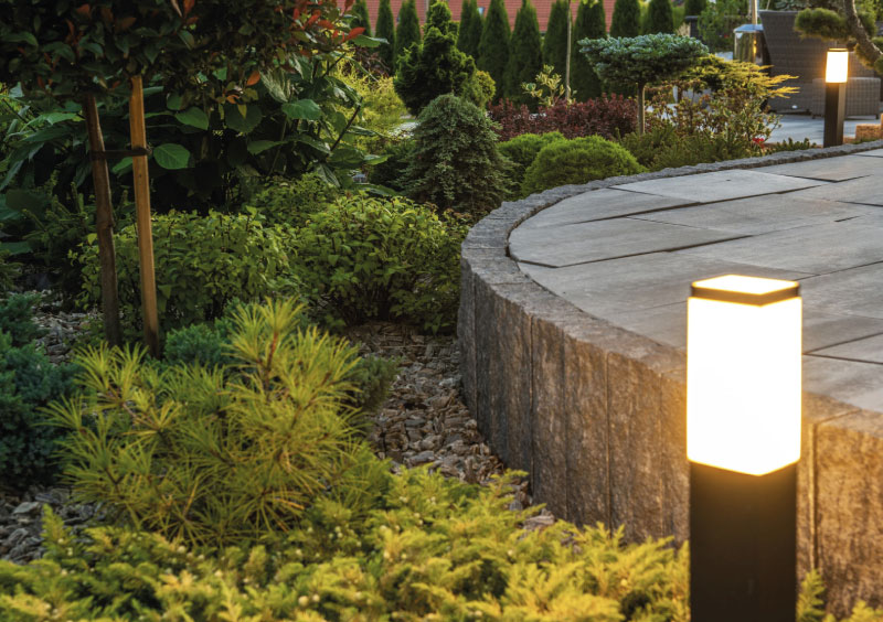 Modern path lighting with bollard fixtures illuminating a landscaped garden patio at dusk