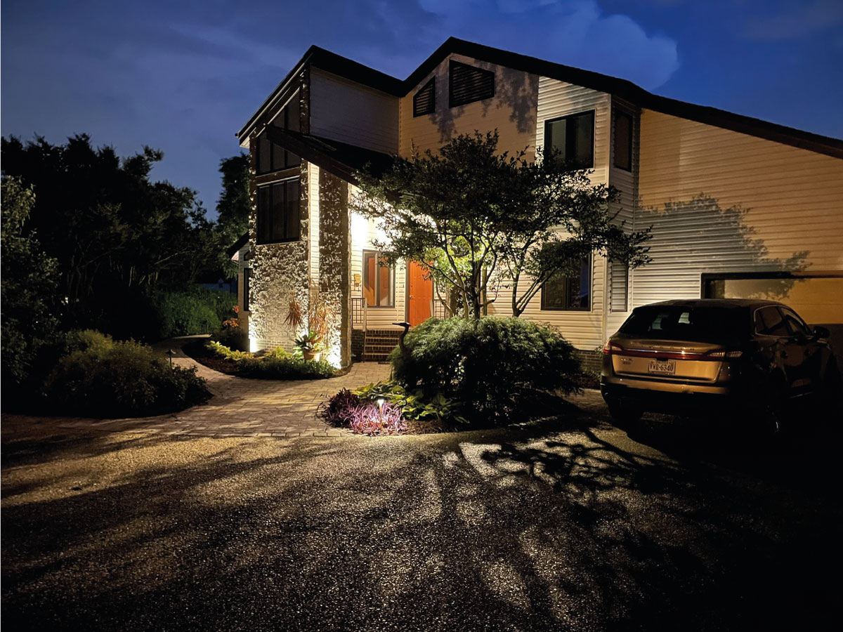 Home exterior with evening landscape lighting on driveway