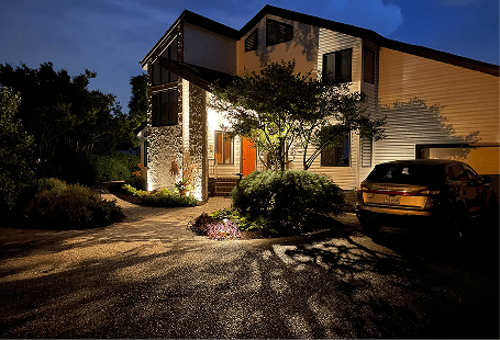 Home exterior with evening landscape lighting on driveway